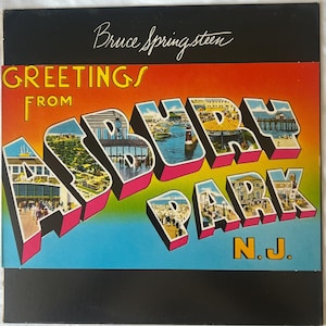 May include: Album cover for Bruce Springsteen's "Greetings from Asbury Park, N.J." featuring a colorful postcard design. The title is in large, 3D letters with images inside, set against a gradient background.