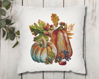 May include: A white throw pillow with a watercolor design of two pumpkins, fall leaves, and berries. The pumpkins are orange and blue with brown stems. The leaves are green, orange, and red. The berries are dark blue.