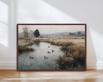 May include: A framed landscape painting depicts a serene river scene with ducks. The artwork features a muted color palette of greens, browns, and grays, with a dark brown frame. The painting evokes a sense of tranquility and natural beauty.