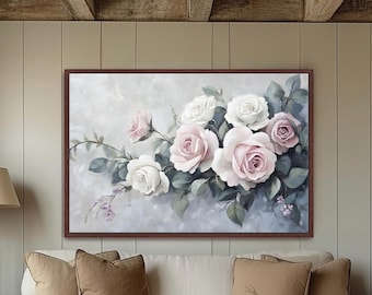 Op de afbeelding: Een ingelijst schilderij van witte en roze rozen met groene bladeren op een lichtgrijze achtergrond. Het kunstwerk wordt tentoongesteld boven een witte bank met bruine kussens.