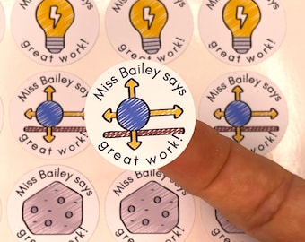 May include: A collection of round stickers with the text "Miss Bailey says great work!" Each sticker features a different hand-drawn graphic: a lightbulb, a compass, and a cookie. The stickers are white with black, yellow, blue, and brown accents.