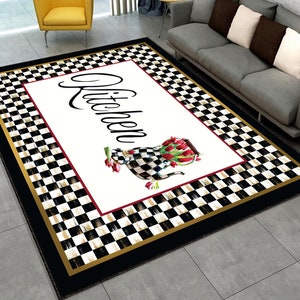 A black and white checkered kitchen rug with a gold border. The rug has a white center with the word "Kitchen" in black script and a watercolor illustration of a teapot with red tulips.