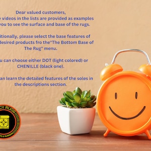 May include: An orange twin-bell alarm clock with a smiling face, a small green succulent in a white square pot, and a circular logo featuring a rug icon and the text FANCY RUGS CARPETS & RUNNERS. Text explains rug base options.
