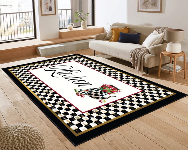 Black and white checkered kitchen rug with a gold border and a white rectangle in the center. The rectangle has the word "Kitchen" written in black cursive script and a red and white floral design.