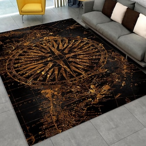 Puede incluir: Una alfombra negra y dorada con un diseño de brújula vintage. La brújula está rodeada de un patrón de mapa.
