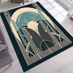 May include: A rectangular rug with an Art Deco design. The rug has a dark teal background with cream and teal geometric shapes, including arches, lines, and a sunburst design. The rug is placed on a light wood floor.