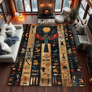 Könnte beinhalten: Ein schwarzer und goldener Teppich mit einem ägyptisch inspirierten Design. Der Teppich zeigt eine große geflügelte Figur in der Mitte, umgeben von kleineren Figuren und Symbolen. Der Teppich liegt auf einem Holzboden in einem Raum mit einem Kamin und großen Fenstern.