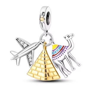 May include: A silver charm bracelet pendant featuring travel-themed charms. The charms include a silver airplane with clear gem accents, a gold pyramid, and a silver camel with colorful saddle details. The pendant has a silver loop for attachment.