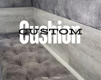 May include: A gray tufted bench cushion with the word "CUSTOM" in white letters on a gray wood-look wall behind it.