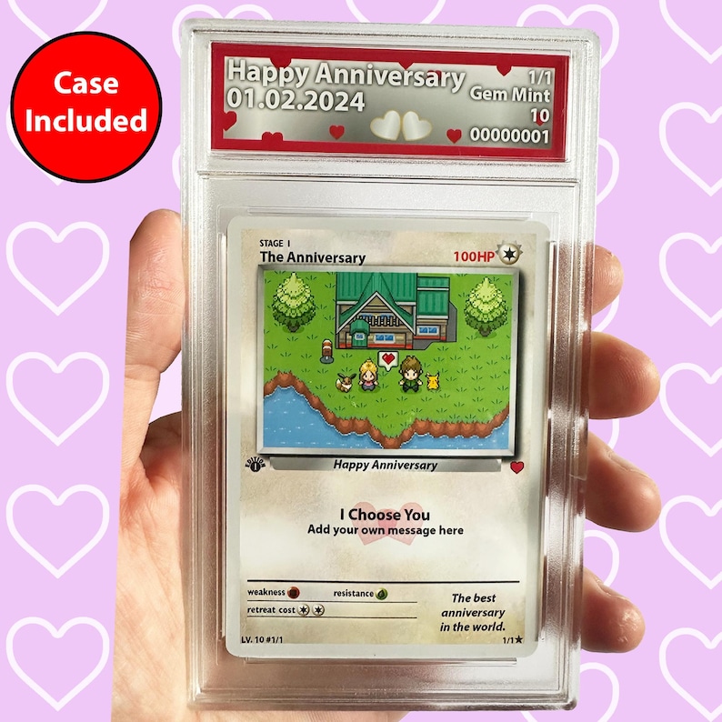 Pode incluir: Um cart&atilde;o de jogo de cartas colecion&aacute;veis com uma imagem pixelada de uma casa e dois personagens. O cart&atilde;o &eacute; intitulado "The Anniversary" e tem uma classifica&ccedil;&atilde;o de 100HP. O cart&atilde;o est&aacute; em uma caixa protetora com um r&oacute;tulo que diz "Happy Anniversary 01.02.2024 Gem Mint 10 00000001".