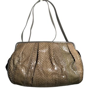 Könnte beinhalten: Eine Vintage-Handtasche mit Schlangenmuster in Braun- und Olivgrüntönen. Die Tasche hat eine strukturierte Form mit geraffter Vorderseite und einem dunkelgrauen Henkel. Die Tasche ist eine Schultertasche.