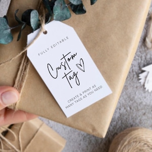 May include: A wrapped gift in brown paper, tied with twine and adorned with eucalyptus. A white tag with the words "Custom Tag" and "Create & Print as Many Tags as You Need" is attached. A small gift box is also visible.