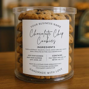 Può includere: Un contenitore di plastica trasparente pieno di biscotti con gocce di cioccolato. I biscotti sono impilati. Un'etichetta bianca sul contenitore mostra il testo "Chocolate Chip Cookies" e gli ingredienti.