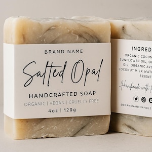 May include: Two bars of handcrafted soap are shown. The front bar has a white label with the words "Salted Opal" and "Handcrafted Soap". The soap is 120g and is organic, vegan, and cruelty-free. The soap has a marbled appearance.