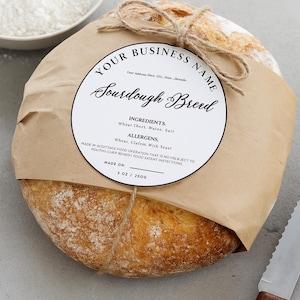 May include: A round loaf of sourdough bread wrapped in brown paper and tied with twine. A circular white label features the text YOUR BUSINESS NAME, Sourdough Bread, INGREDIENTS, Wheat Thert, Watee, Salt, ALLERGENS, Wheat, Clafem, With Yeast, and 3 OZ / 250G.