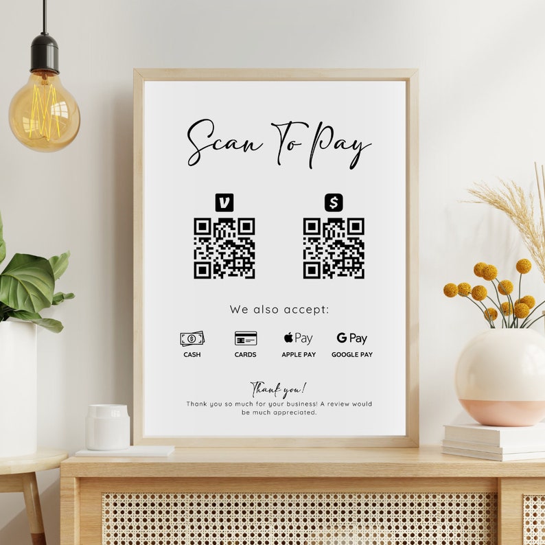 May include: A white sign with black text that reads "Scan To Pay".  Two black and white QR codes are displayed, one labeled "V" and the other labeled "$".  Below the QR codes, the sign reads "We also accept:" and lists the following payment methods: "Cash", "Cards", "Apple Pay", and "Google Pay".  The sign concludes with "Thank you! Thank you so much for your business! A review would be much appreciated."