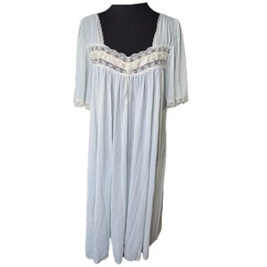 May include: A light blue nightgown with a square neckline and short sleeves. The nightgown features cream-colored lace trim around the neckline and sleeves. A drawstring detail is visible at the bust. The gown is displayed on a black mannequin.