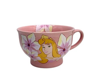 Taza de café/té Aurora de La Bella Durmiente de Disney Store, mariposa rosa y flor, en excelente estado.