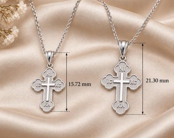 May include: Two silver-toned cross pendants on matching chains. Each cross features a central raised cross design with the inscription IC XC NI KA. The smaller pendant measures 15.72 mm in height, while the larger pendant measures 21.30 mm in height.