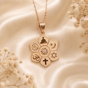 May include: A rose gold-toned pendant necklace featuring a six-petaled flower design. Each petal displays a different religious or spiritual symbol, including a cross, Star of David, crescent moon, star, Om, Buddha, and yin-yang, with a sunburst center.