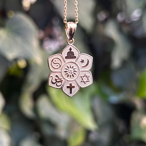 Könnte beinhalten: Eine goldene Halskette mit einem Anhänger in Form einer Blume, der Symbole verschiedener Religionen zeigt, darunter ein Kreuz, ein Davidstern, eine Mondsichel, ein Yin-Yang-Symbol und ein Om-Symbol.