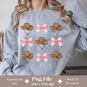 May include: A grey sweatshirt with a repeating pattern of brown cowboy hats and pink bows. The text "Png File 300 x 300 dpi" is printed on the bottom of the sweatshirt.