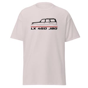 May include: A light-colored t-shirt featuring a black line-art illustration of an SUV in profile. Below the vehicle graphic is a thin horizontal red line and the black text LX 450 J80, centered on the chest of the garment.
