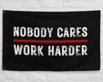 Peut inclure: Une bannière murale rectangulaire noire avec le texte blanc vieilli NOBODY CARES WORK HARDER sur deux lignes, séparé par une ligne rouge horizontale. La bannière comporte des œillets métalliques aux coins pour l'accrocher au mur.