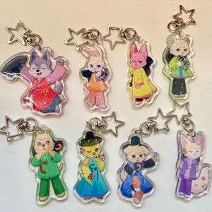 May include: A collection of eight acrylic keychains featuring cartoon animal characters in colorful traditional Korean clothing. Each keychain has a star-shaped clasp. The animals include a wolf, rabbit, pink rabbit, mouse, cat, duck, dog, and fox.