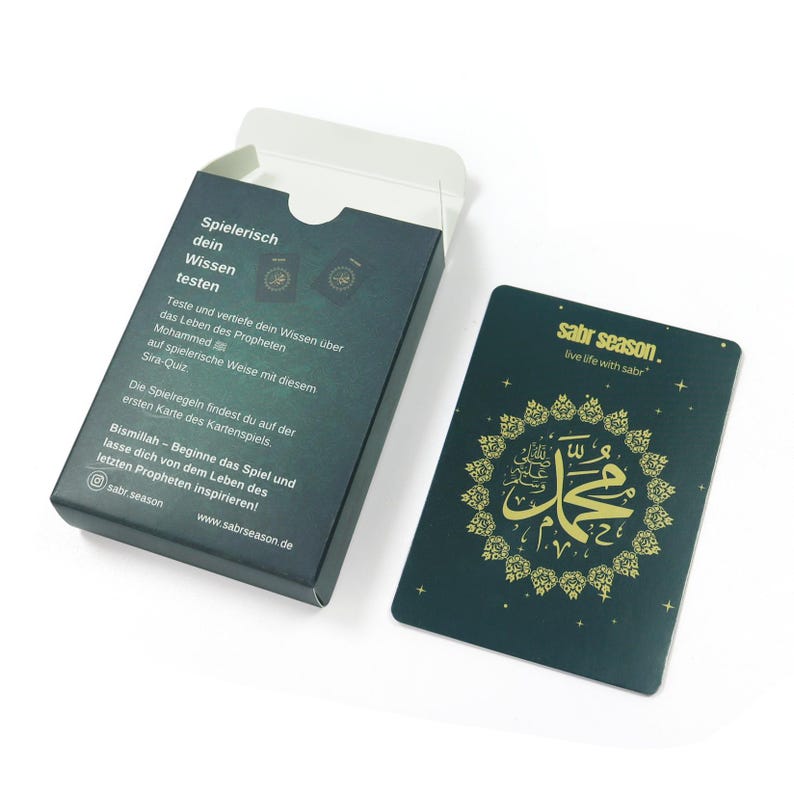 May include: A green card game box with gold lettering that says "Spielerisch dein Wissen testen" and "sabr season. live life with sabr". The box has a picture of a card with gold Arabic calligraphy on a green background.