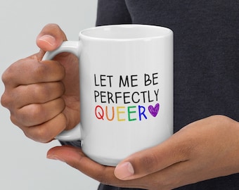 May include: White ceramic coffee mug with the text "Let me be perfectly QUEER" in black lettering with a rainbow colored "QUEER" and a purple heart.