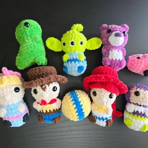 Puede incluir: Una colecci&oacute;n de nueve juguetes de peluche tejidos a crochet, que incluyen un extraterrestre verde, un oso morado, un cerdo rosa, una pelota amarilla y azul, un vaquero, una princesa, un personaje pelirrojo y otros dos personajes.