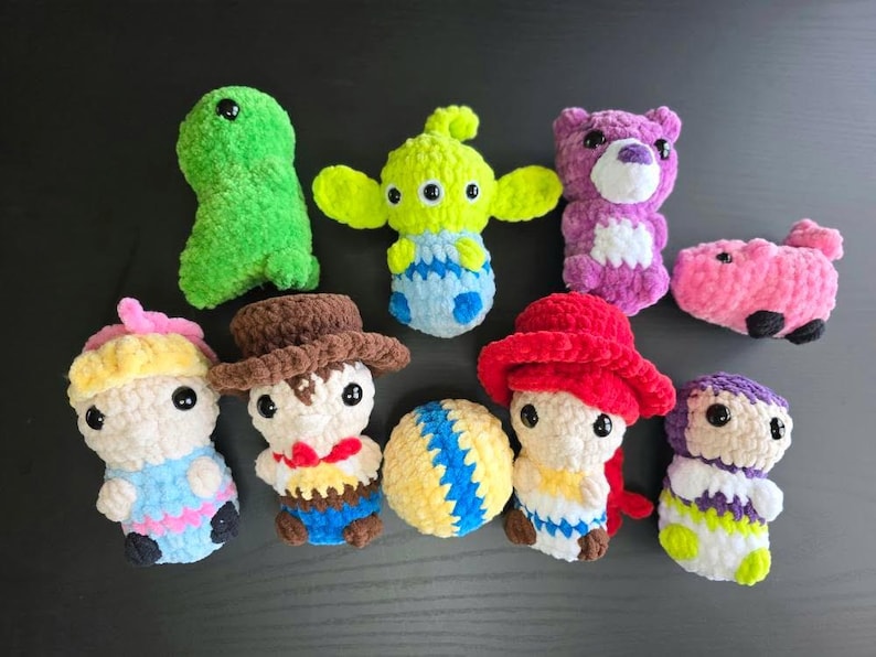 Puede incluir: Una colecci&oacute;n de nueve juguetes de peluche tejidos a crochet, que incluyen un extraterrestre verde, un oso morado, un cerdo rosa, una pelota amarilla y azul, un vaquero, una princesa, un personaje pelirrojo y otros dos personajes.