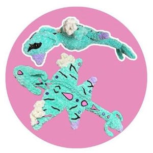 May include: Two plush toys in a pink circle. The toys are teal with black, white, pink, and purple accents. One toy is a long, slender shape, and the other is a more complex, multi-part design.