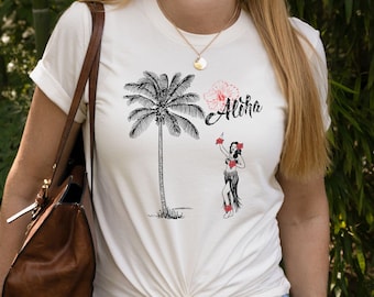 May include: White t-shirt with a black and white illustration of a palm tree and a hula dancer. The shirt also has the word "Aloha" written in red and black.
