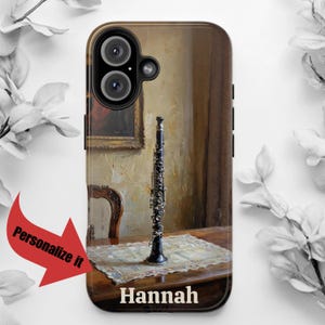 May include: A black and silver clarinet on a wooden table with a white doily. The table is in a room with a painting on the wall. The phone case has the name "Hannah" printed on the bottom.