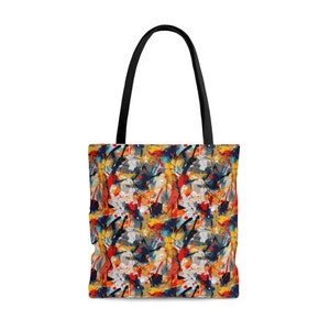 Puede incluir: Una bolsa de mano negra con un diseño abstracto colorido. El diseño presenta salpicaduras de pintura roja, amarilla, azul y naranja sobre un fondo blanco.