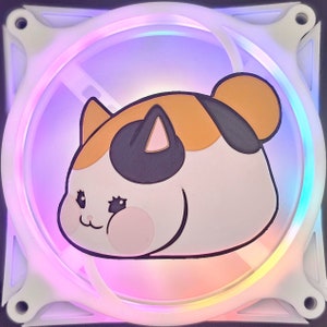 May include: A white computer fan with a colorful LED light ring. The fan features a cartoon cat face in orange, black, and white. The cat has pink cheeks and a smiling expression. The fan is designed for computer cooling.