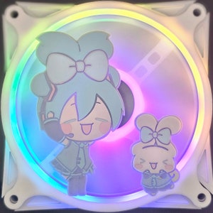 Könnte beinhalten: Ein weißer Computerlüfter mit farbenfroher LED-Lichtanzeige. Der Lüfter hat zwei Aufkleber mit Cartoon-Charakteren mit blauen Haaren und Schleifen. Das Design des Lüfters ist eine Mischung aus Weiß, Blau, Rosa und Gelb.