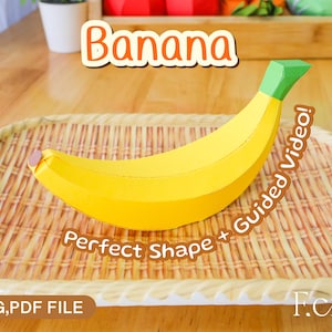 May include: A paper banana with a yellow peel and green stem sits on a woven tray. The word "Banana" is written above the banana. The text "Perfect Shape + Guided Video!" is also visible.