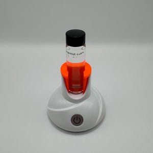 May include: A white and orange device with a clear glass tube and a black lid. The tube is labeled "against.com". The device has a power button on the front.