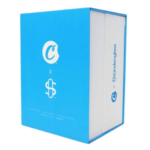 May include: A rectangular box with a light blue exterior and white interior. The box features the "Cookies" logo and the "Stündenglass" logo. The box has text in multiple languages.