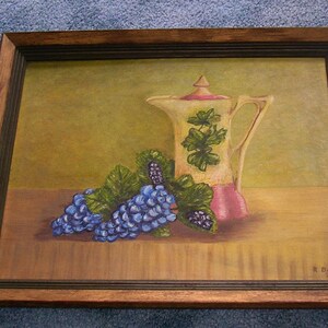 May include: A framed painting of a still life featuring a white pitcher with a pink base and green floral design, a bunch of purple grapes with green leaves, and a brown wooden table. The painting is signed "R. Davis 28".