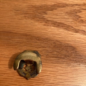 Puede incluir: Una perilla de puerta decorativa de metal dorado con un dise&ntilde;o floral. La perilla tiene una parte superior redondeada y un anillo decorativo alrededor de la base. La perilla est&aacute; marcada con el texto "1828".