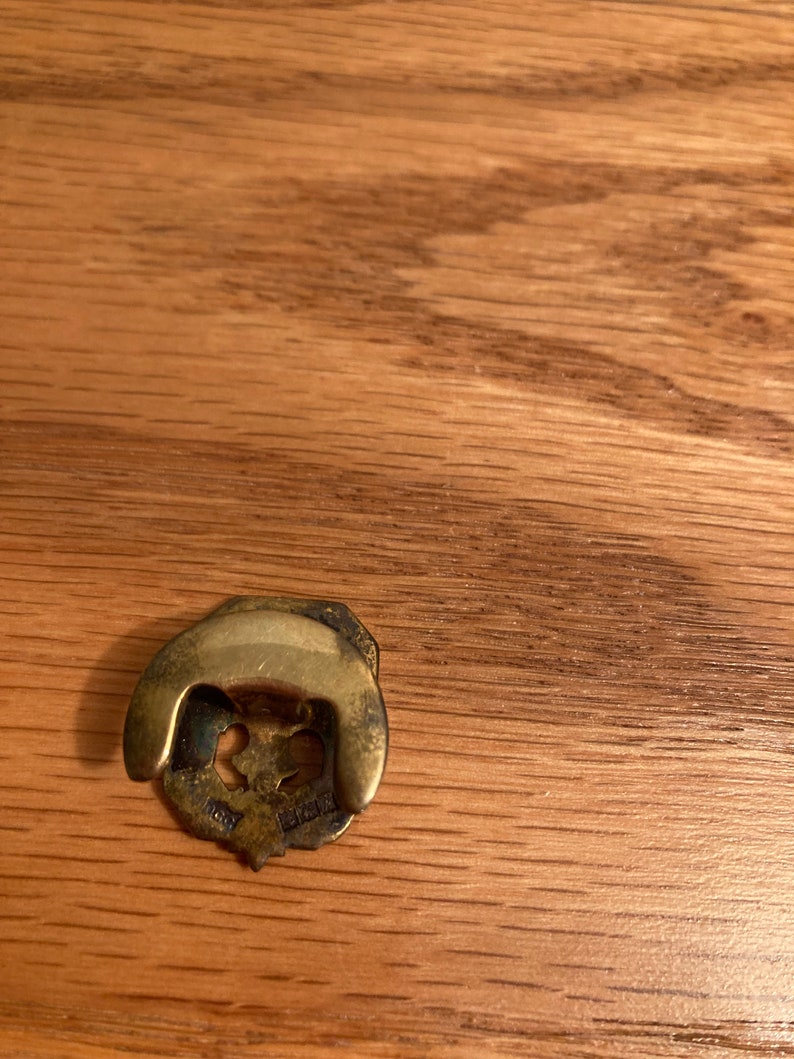 Puede incluir: Una perilla de puerta decorativa de metal dorado con un dise&ntilde;o floral. La perilla tiene una parte superior redondeada y un anillo decorativo alrededor de la base. La perilla est&aacute; marcada con el texto "1828".