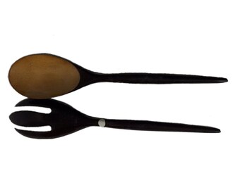 May include: A wooden salad serving set with a brown spoon and a black fork.