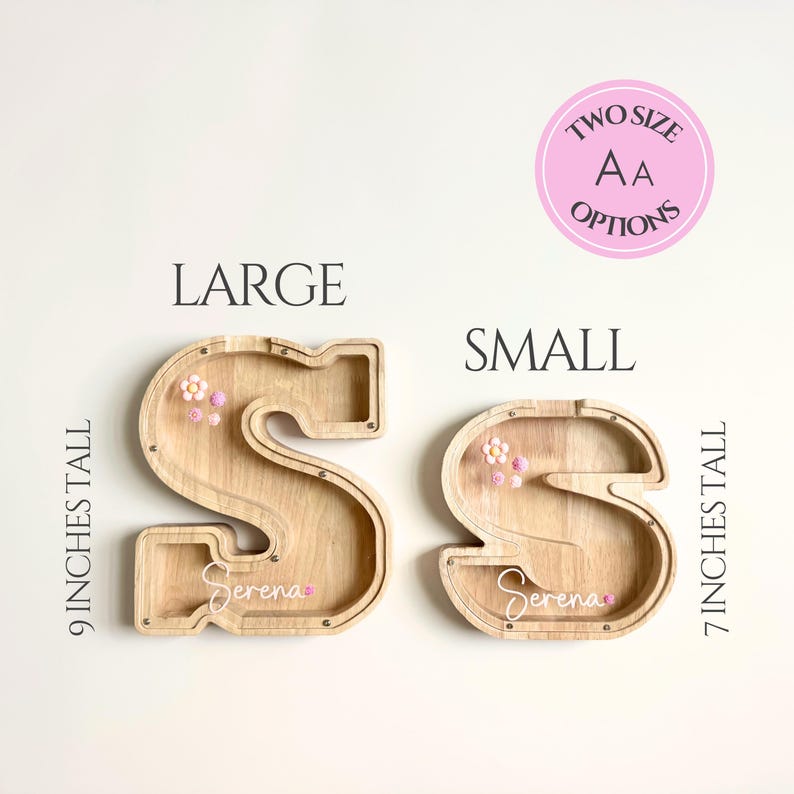 May include: Two wooden letter "S" shaped piggy banks, one large and one small, with the text "Serena" on each. The large bank is 9 inches tall, and the small bank is 7 inches tall. Both banks have decorative flowers.