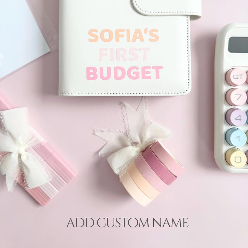 Może przedstawiać: Biały planer budżetowy z napisem "SOFIA'S FIRST BUDGET" w pastelowych kolorach. Widoczny jest r&oacute;wnież pastelowy kalkulator i dekoracyjne wstążki. Tekst "ADD CUSTOM NAME" znajduje się na dole.
