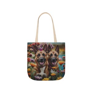 Op de afbeelding: Tote bag met een levendige afbeelding van twee honden die glimlachen te midden van een kleurrijk bloemenveld. De tas heeft een crèmekleurige handgreep en een rechthoekig ontwerp.