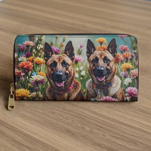 以下が含まれることがあります： 2匹のジャーマンシェパード犬と鮮やかな花の模様が特徴のジッパー付き財布。財布は金色のジッパープルが付いており、木製のテーブルの上に置かれています。